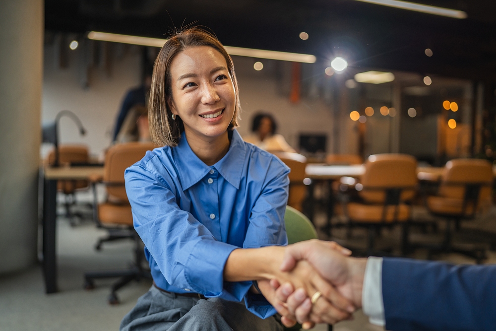 Businesswoman and businessman shaking hands in an office meeting